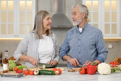 Happy senior couple cooking together in kitchen