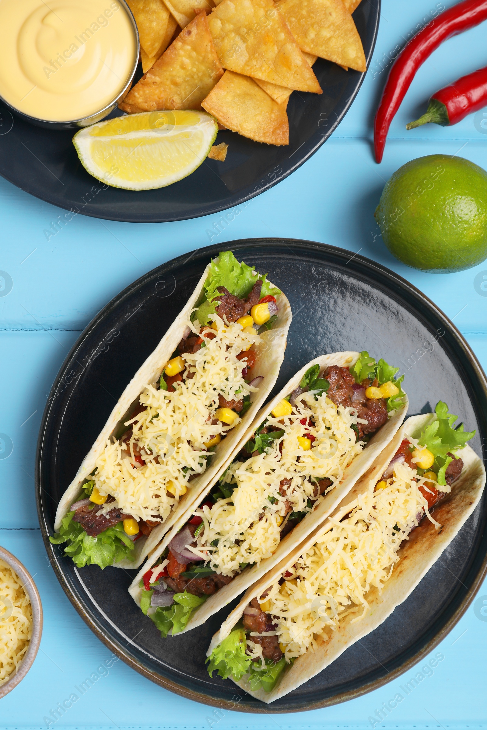 Photo of Flat lay composition with delicious tacos on light blue wooden table