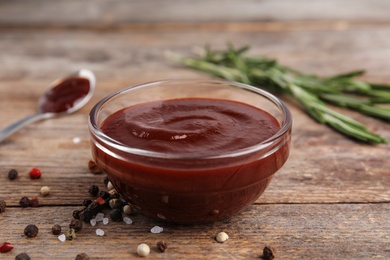 Photo of Composition with bowl of barbecue sauce on wooden table