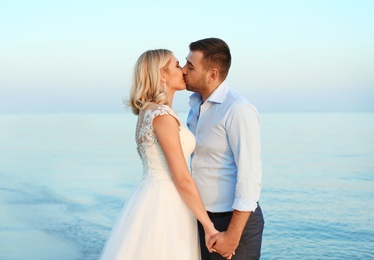 Photo of Wedding couple. Groom kissing bride on beach