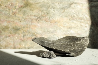 Photo of Presentation of product. Podium made of stones on light textured table. Space for text