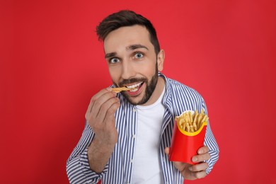 Photo of Man eating French fries on red background
