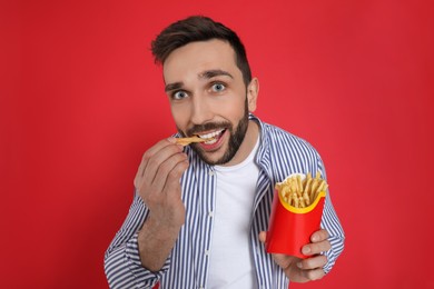 Man eating French fries on red background