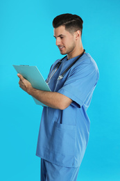 Handsome doctor with clipboard on blue background