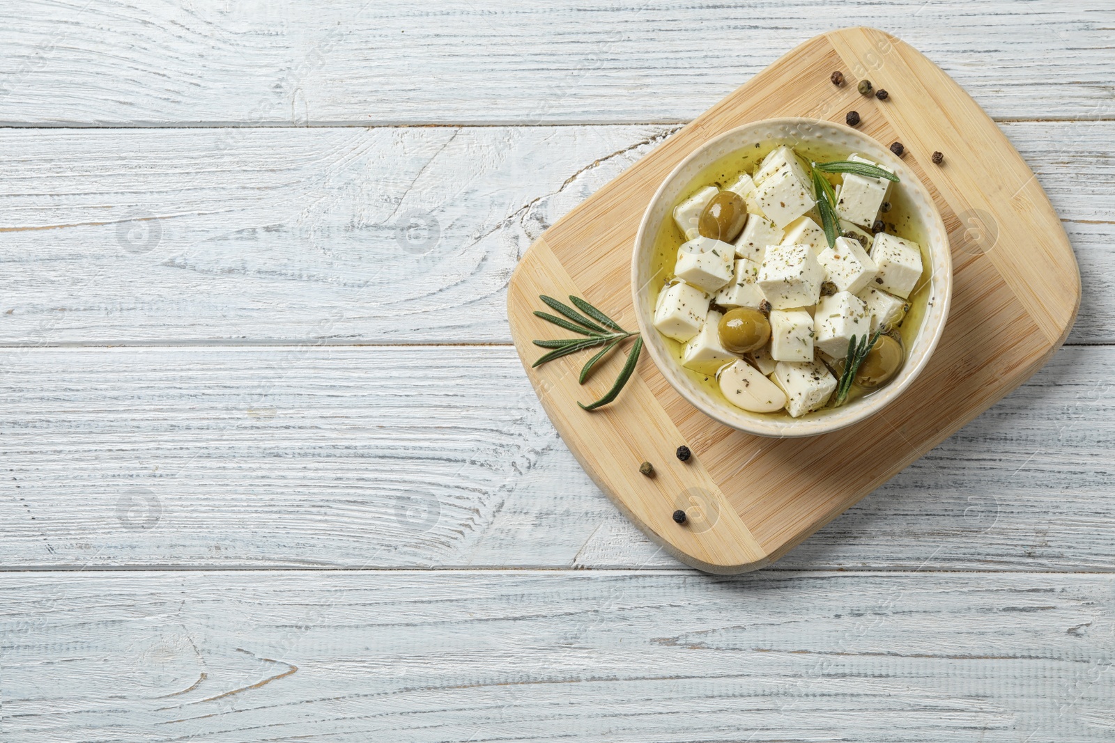 Photo of Flat lay composition with pickled feta cheese in bowl on white wooden table, space for text