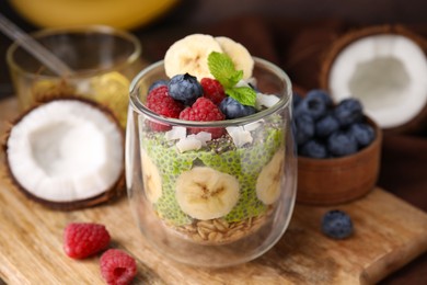 Photo of Tasty oatmeal with chia matcha pudding and fruits on wooden board, closeup. Healthy breakfast