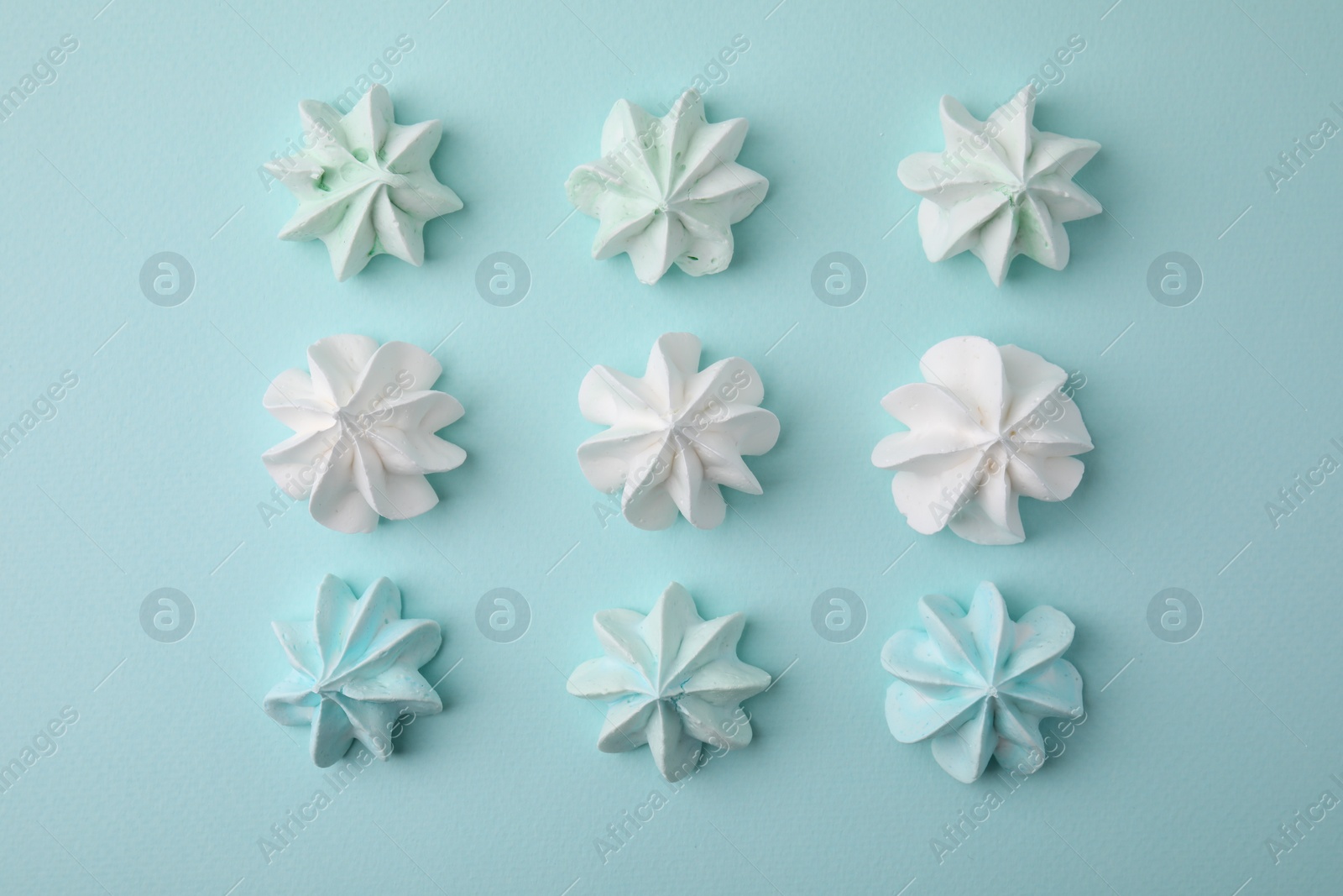 Photo of Delicious meringue cookies on light blue background, flat lay