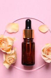 Photo of Bottle of cosmetic serum, flowers and petals on pink background, flat lay