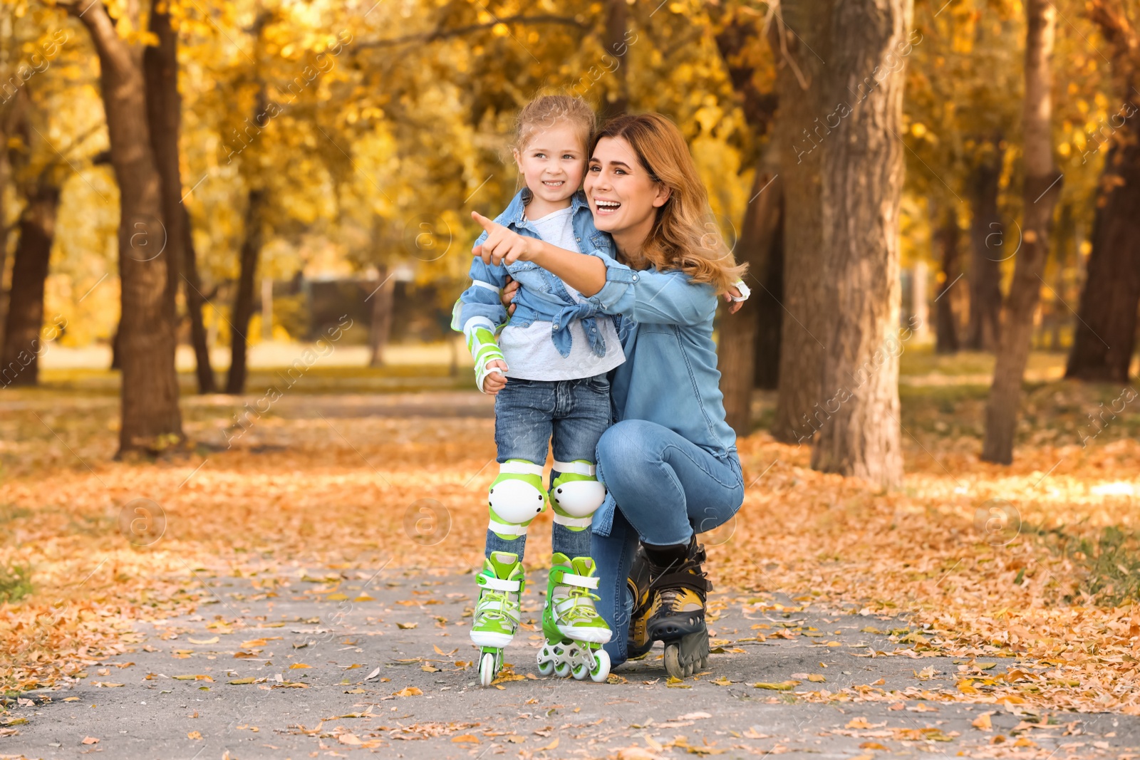Photo of Mother and her daughter wearing roller skates in autumn park