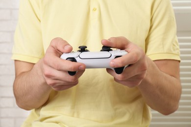 Man using wireless game controller indoors, closeup