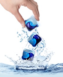 Woman throwing laundry capsules into water on white background, closeup. Detergent pods