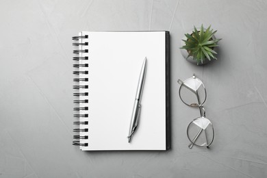 Photo of Ballpoint pen, notebook and glasses on light gray table, flat lay