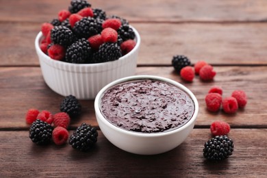 Blackberry puree in bowl and fresh berries on wooden table