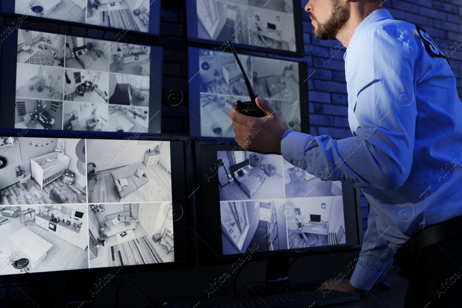 Photo of Male security guard with portable transmitter monitoring modern CCTV cameras indoors