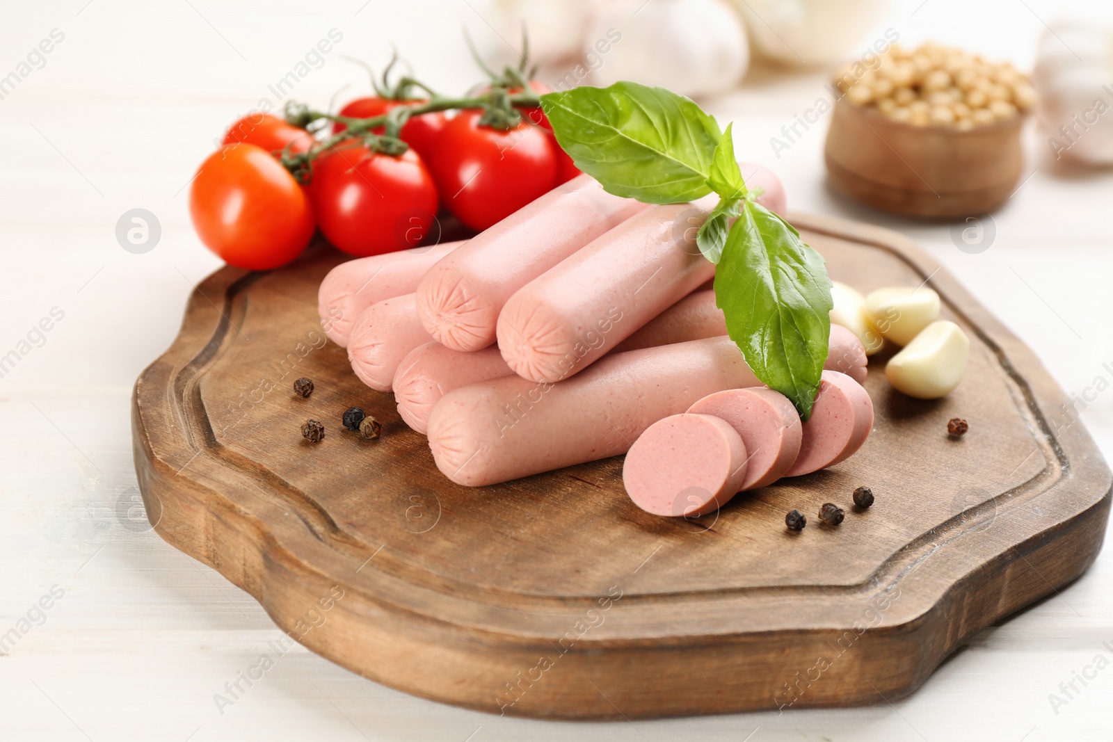 Photo of Fresh raw vegetarian sausages and vegetables on white wooden table