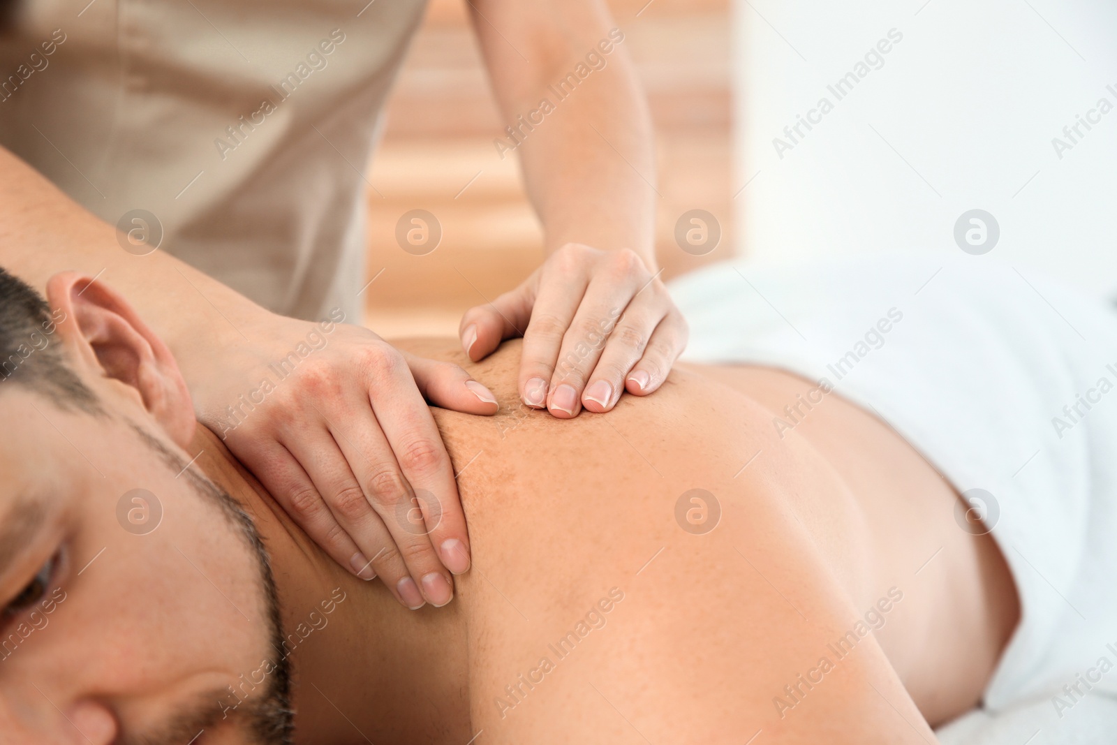 Photo of Handsome man receiving back massage in spa salon, closeup