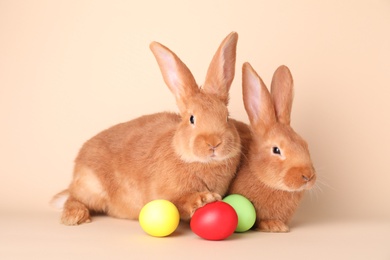 Photo of Cute bunnies and Easter eggs on beige background