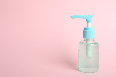 Dispenser bottle with antiseptic gel on pink background. Space for text