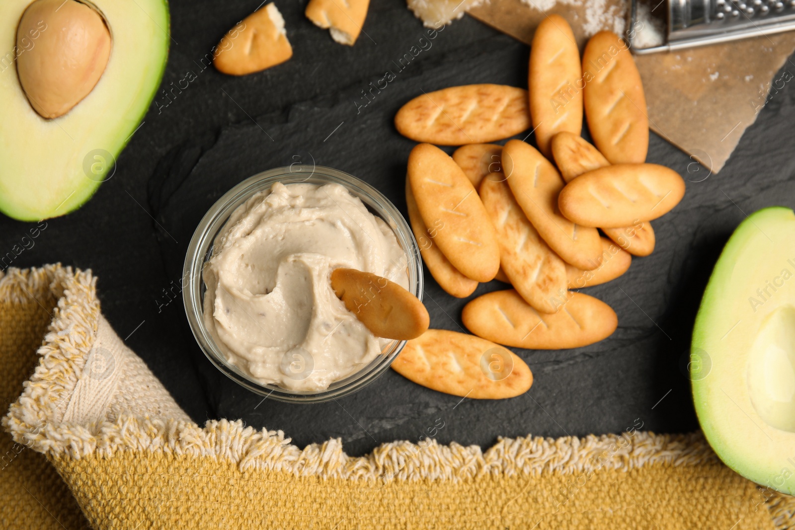 Photo of Delicious crackers and humus on black table, flat lay