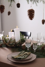 Photo of Christmas table setting with burning candles and other festive decor