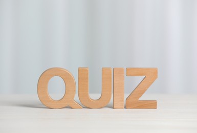 Photo of Word Quiz made with wooden letters on white table