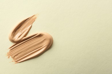 Photo of Sample of liquid skin foundation on beige background, top view. Space for text