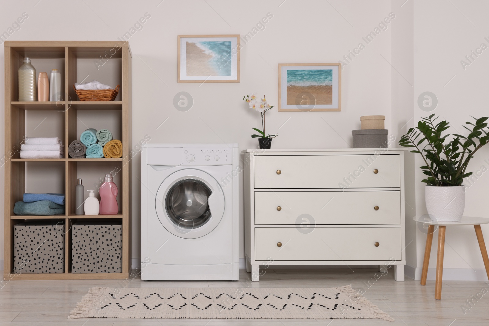 Photo of Stylish laundry room with washing machine and chest of drawers. Interior design