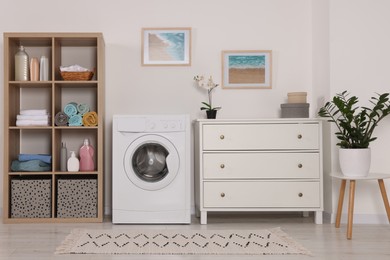 Photo of Stylish laundry room with washing machine and chest of drawers. Interior design
