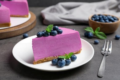 Photo of Plate with piece of tasty blueberry cake on grey table