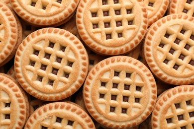 Tasty sandwich cookies with cream as background, top view