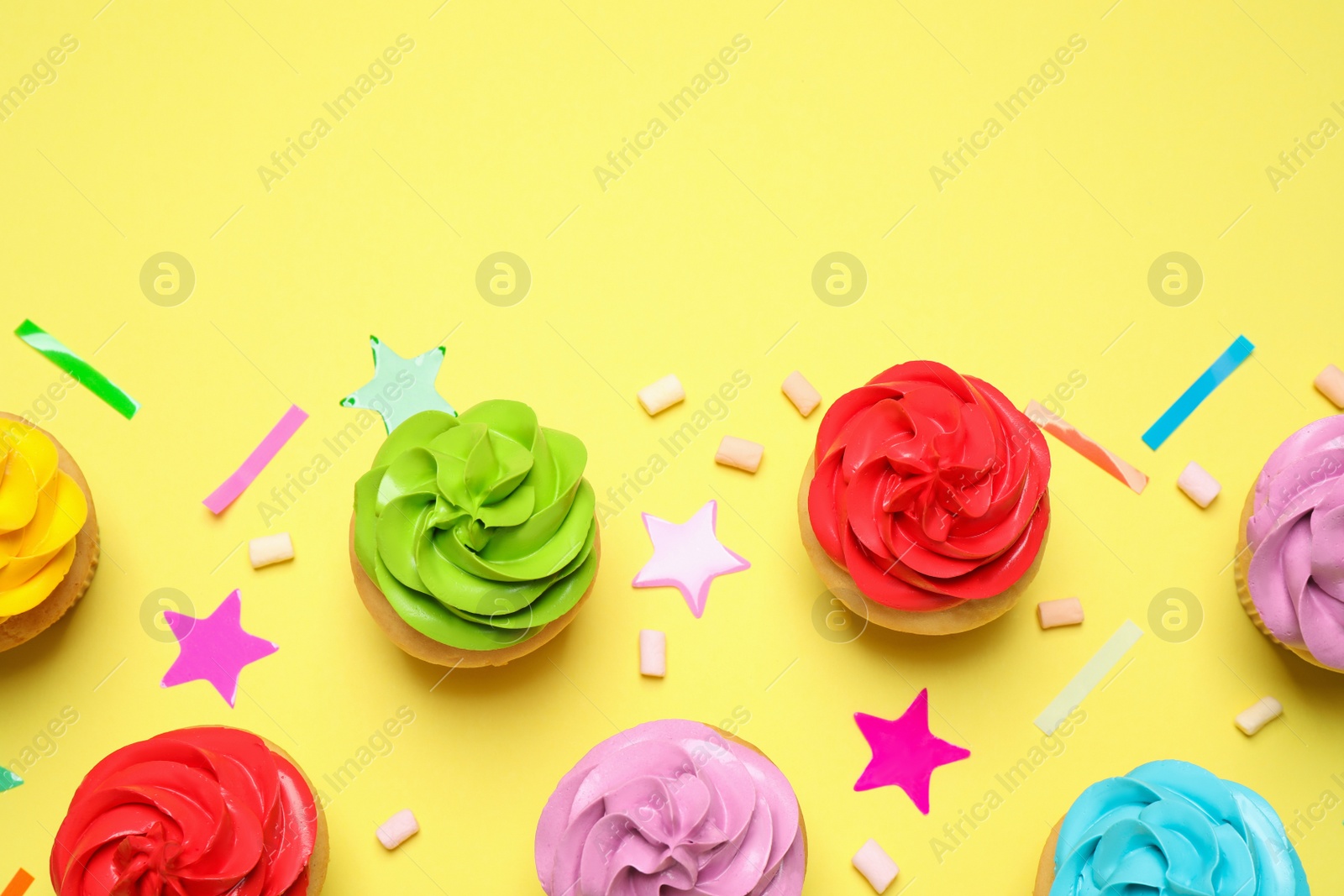 Photo of Colorful birthday cupcakes on yellow background, flat lay. Space for text