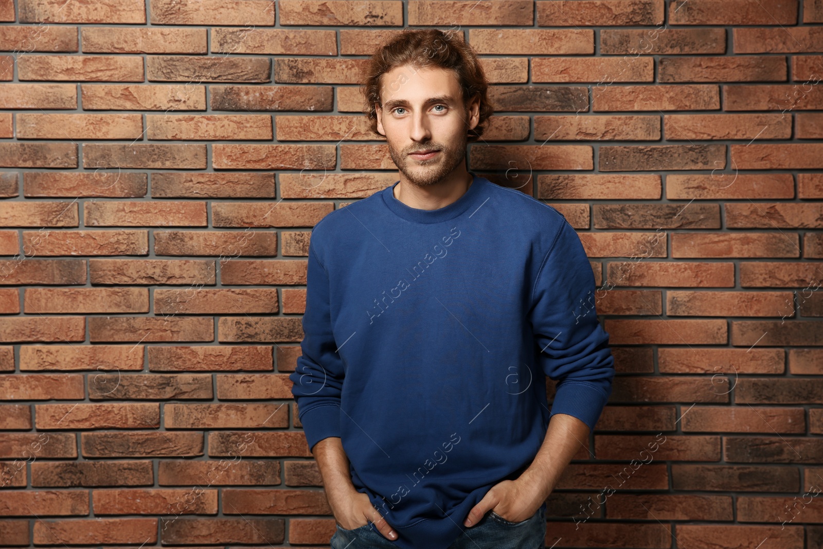 Photo of Handsome young man in warm sweater near brick wall