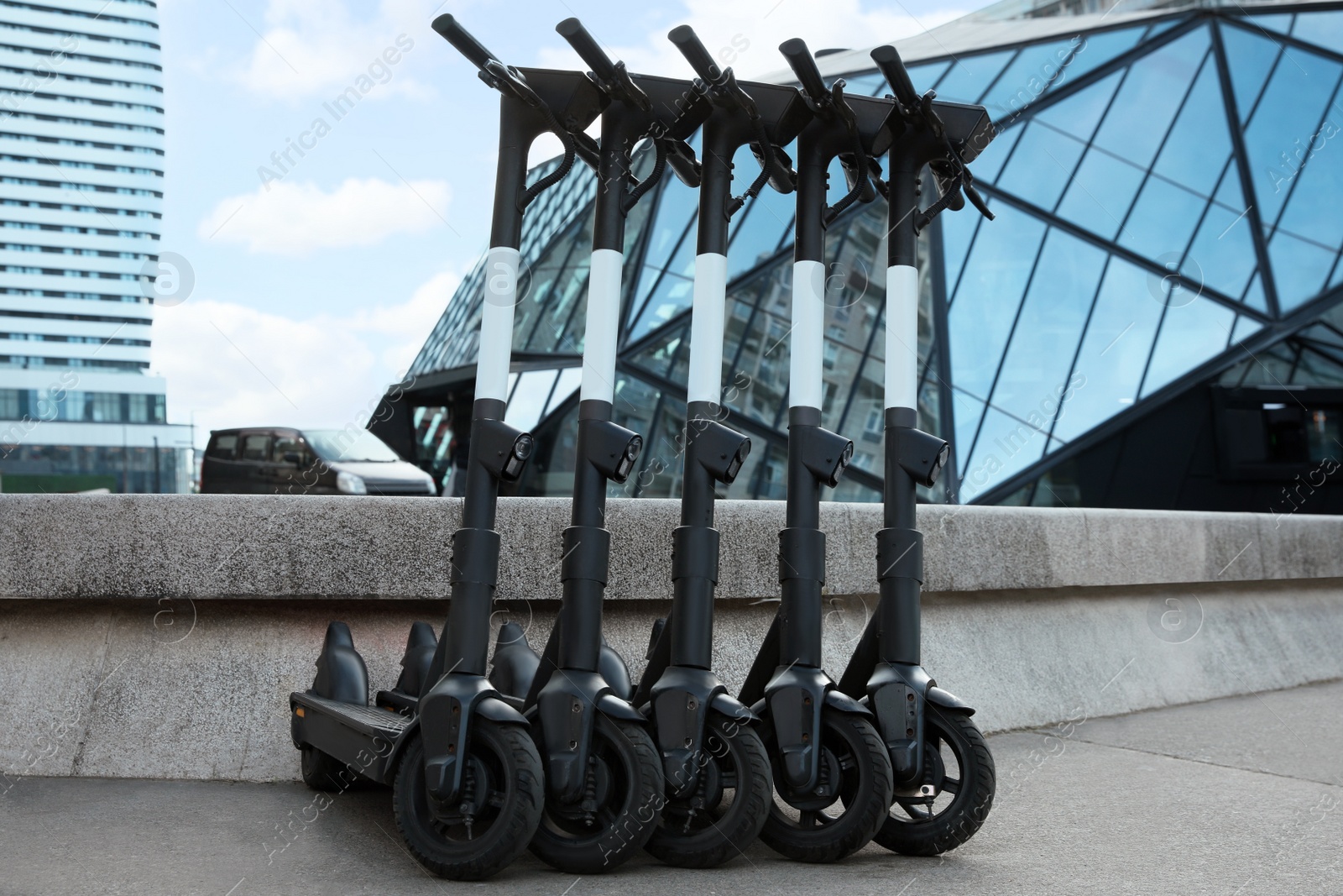 Photo of Row of electric scooters on city street. Rental service