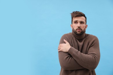 Photo of Man suffering from fever on light blue background, space for text. Cold symptoms
