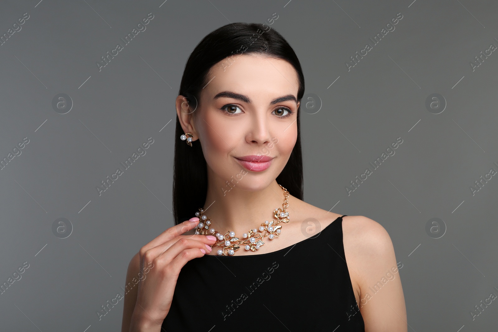 Photo of Beautiful young woman with elegant jewelry on dark grey background