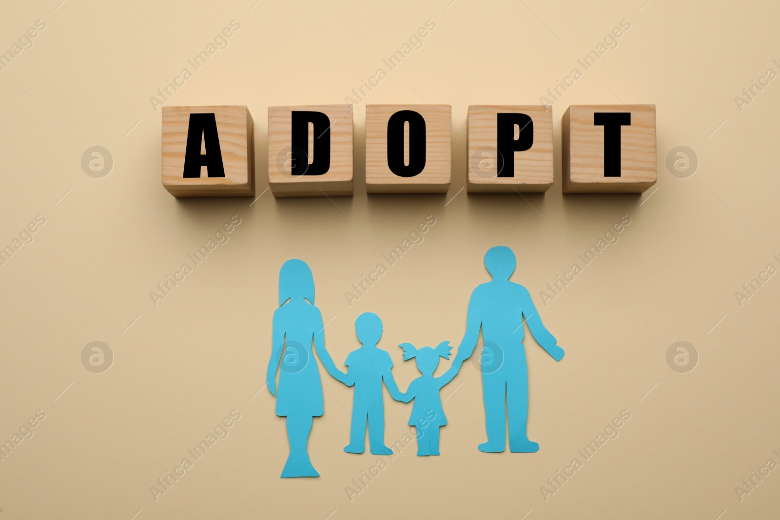 Photo of Family figure and word Adopt made of cubes on beige background, flat lay