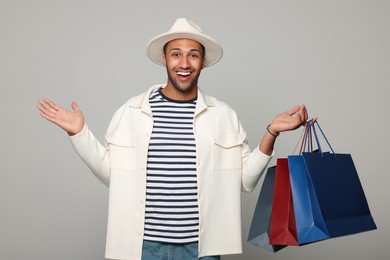 Photo of Happy African American man in hat with shopping bags on light grey background