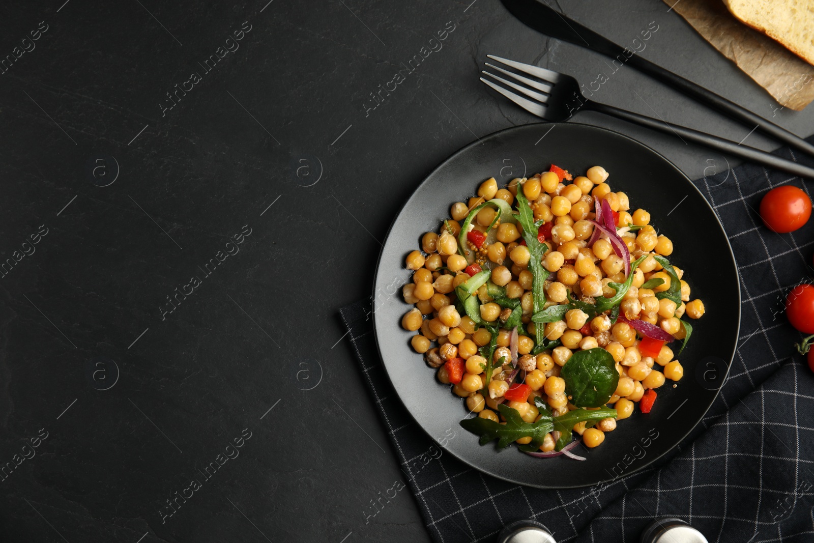 Photo of Delicious fresh chickpea salad served on black table, flat lay. Space for text