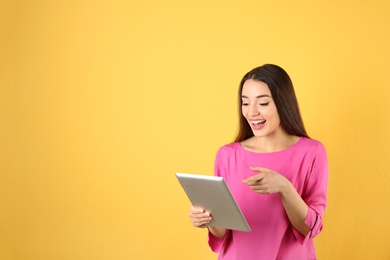 Photo of Woman using tablet for video chat on color background. Space for text