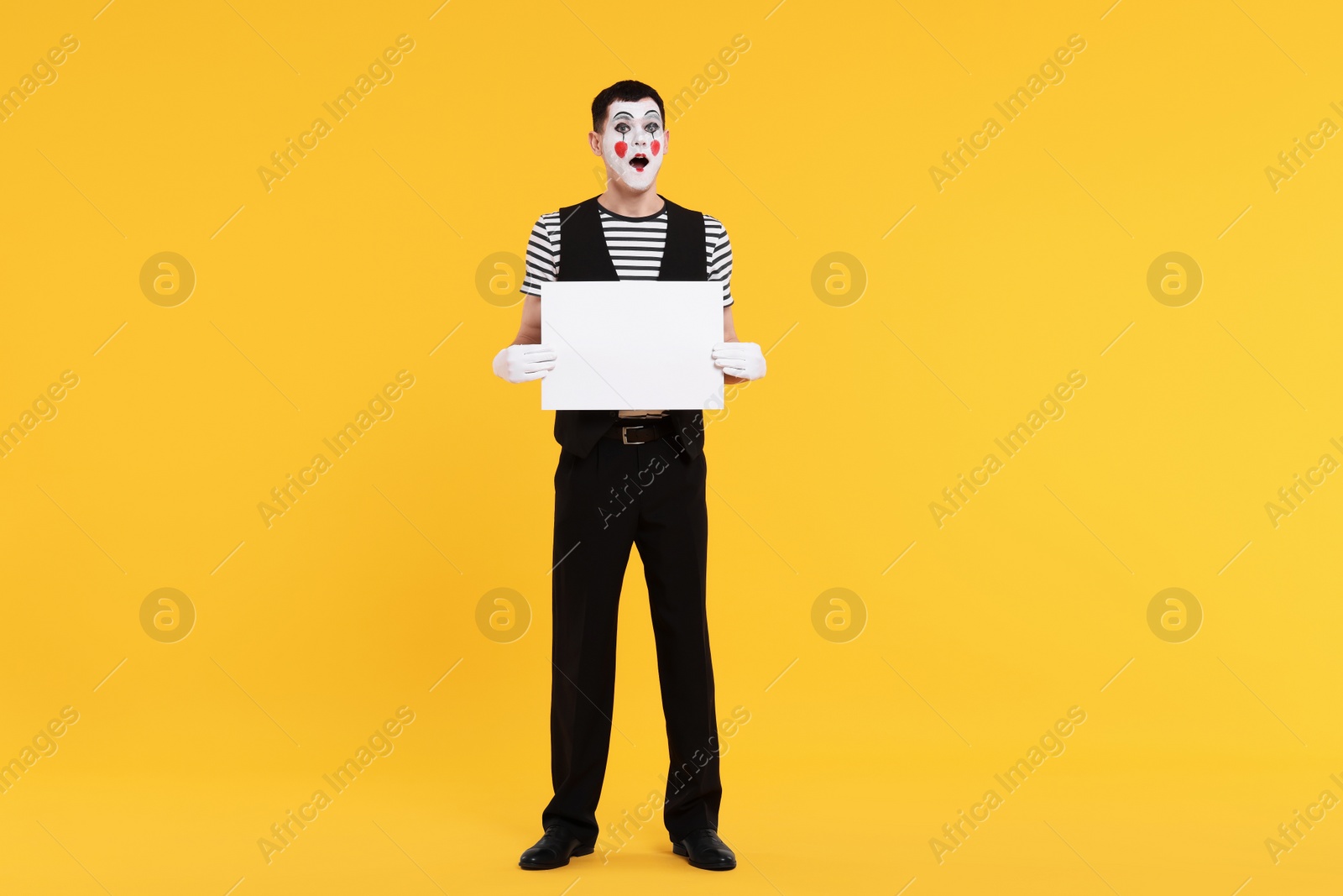 Photo of Funny mime artist with blank sign on orange background