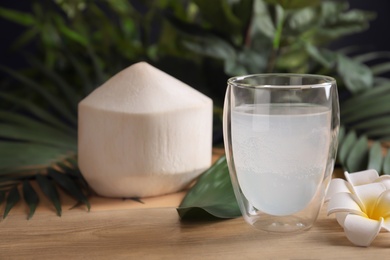 Photo of Glass with fresh coconut water on wooden table