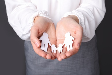 Photo of Woman holding cutout paper family, closeup. Life insurance concept