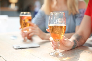 Young women with glasses of cold beer at table