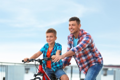 Dad teaching son to ride bicycle outdoors