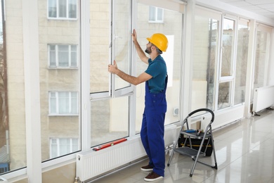 Photo of Construction worker installing plastic window in house