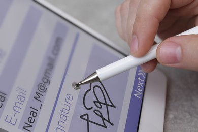 Image of Electronic signature. Man using stylus and tablet at table, closeup