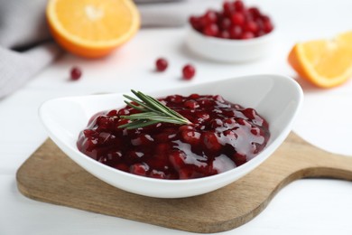 Photo of Fresh cranberry sauce and rosemary in bowl on white table, closeup