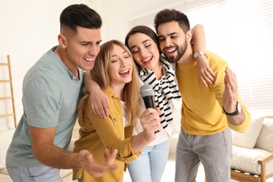 Photo of Happy friends singing karaoke together at home