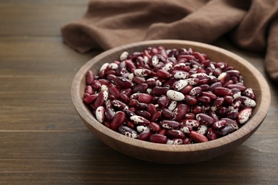 Photo of Bowl with dry kidney beans on wooden table