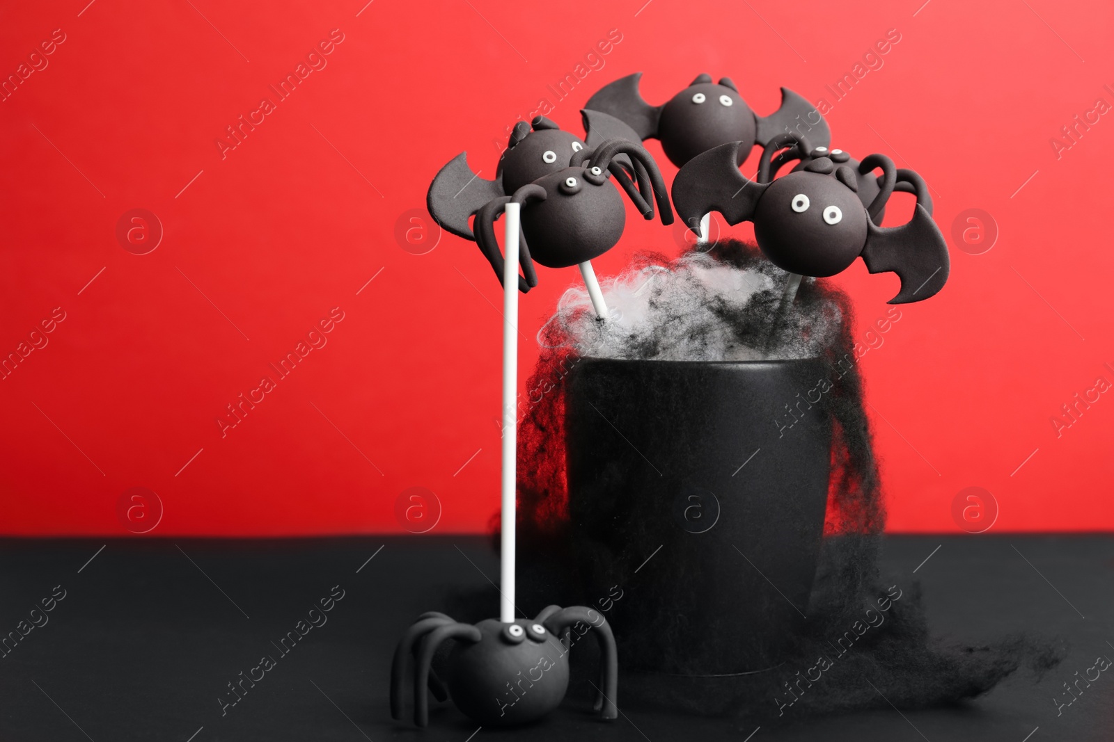 Photo of Delicious Halloween themed cake pops on red background